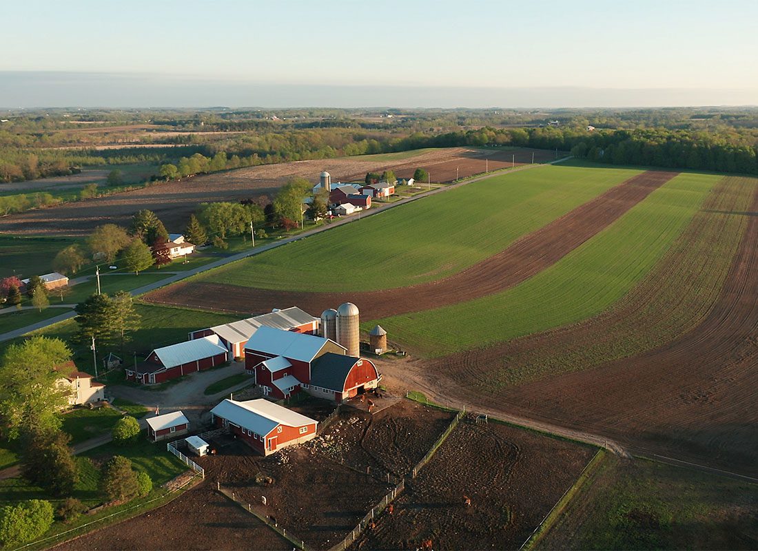 Insurance by Industry - Aerial View of a a Red Barn and Other Farm Buildings with Grain Silos on a Small Farm with Open Fields in Wisconsin