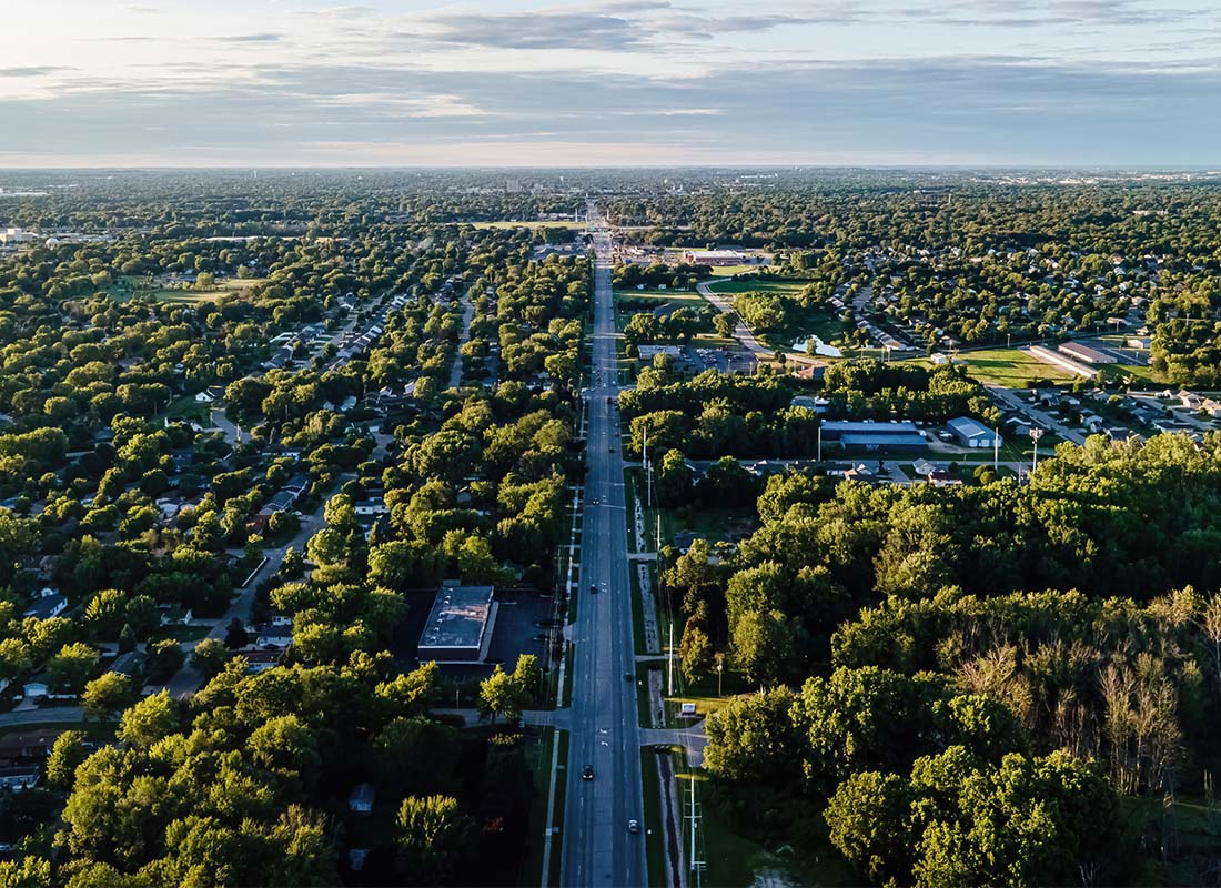 Menasha, WI - Aerial View of Homes and Buildings Surrounded by Vibrant Green Trees with a Highway in the Middle in Menasha Wisconsin