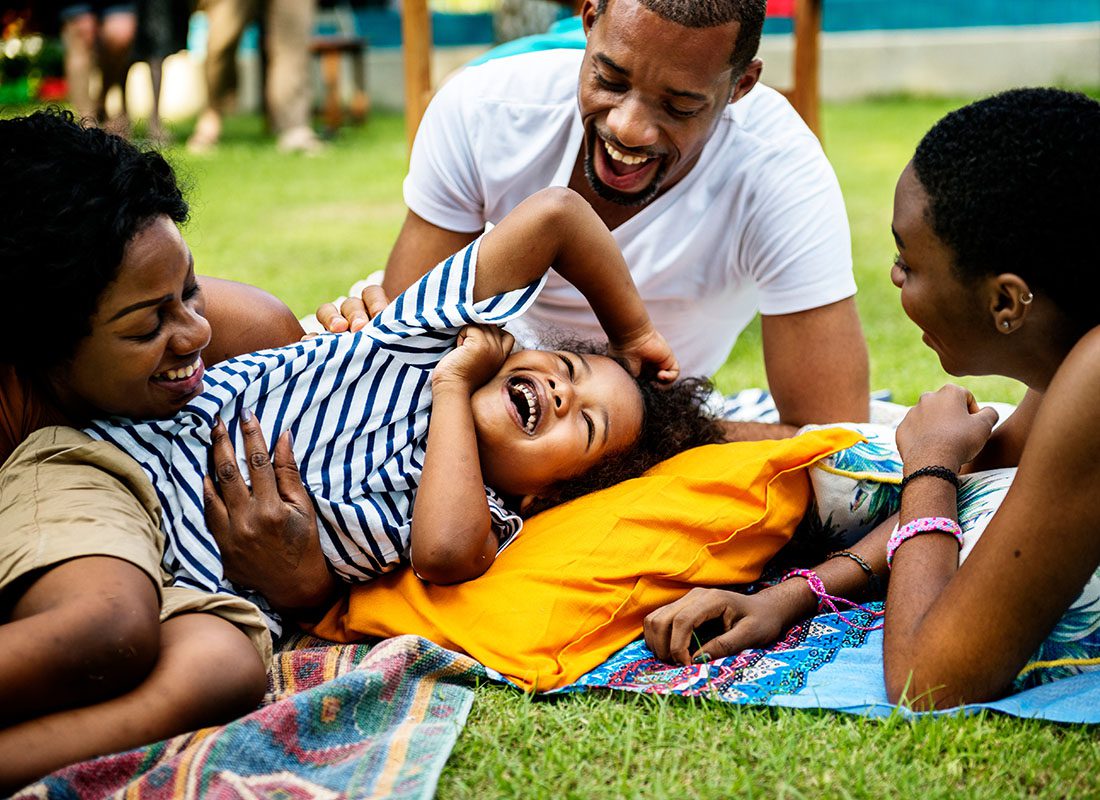 Personal Insurance - Closeup View of a Cheerful Family Having Fun Playing Outside with an Excited Young Boy on the Green Grass in the Backyard